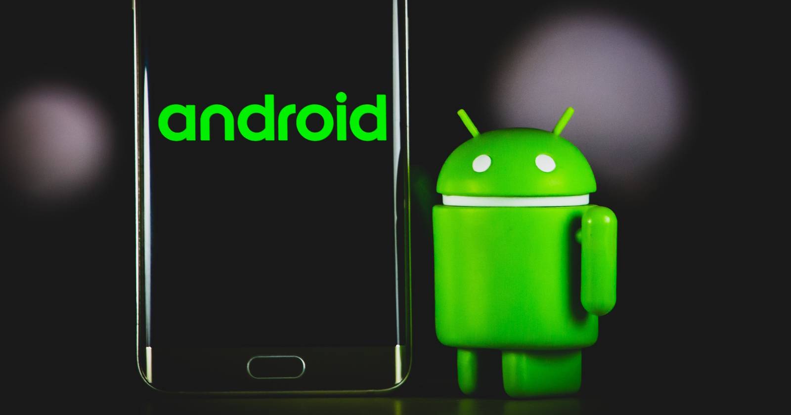 Робот Android рядом с экраном смартфона с надписью Android