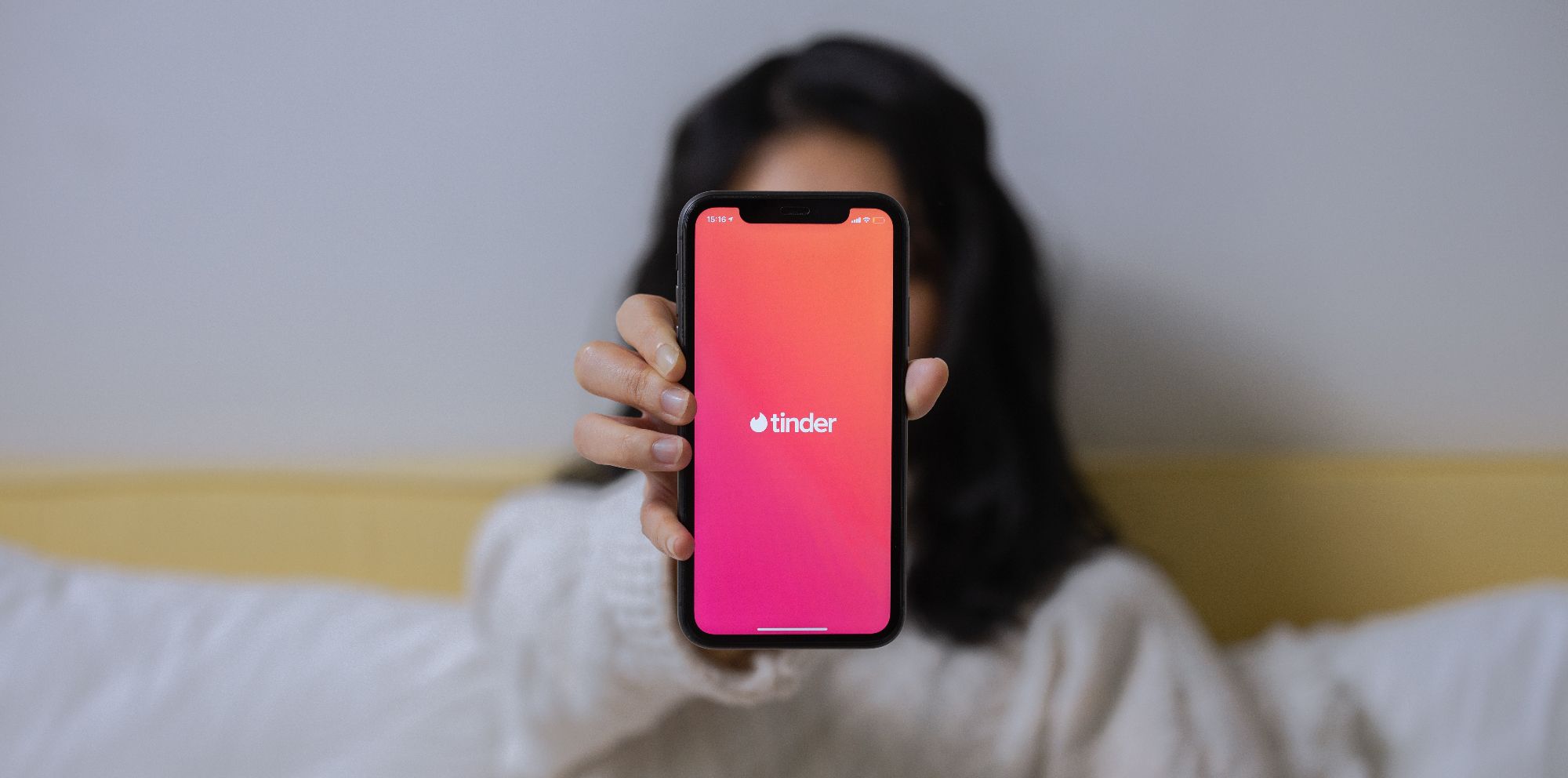 Женщина держит телефон с открытым приложением Tinder