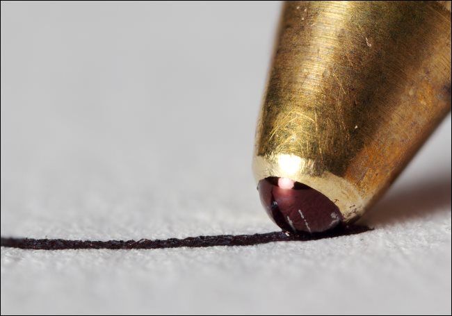 Крупный план наконечника шариковой ручки, пишущей на бумаге