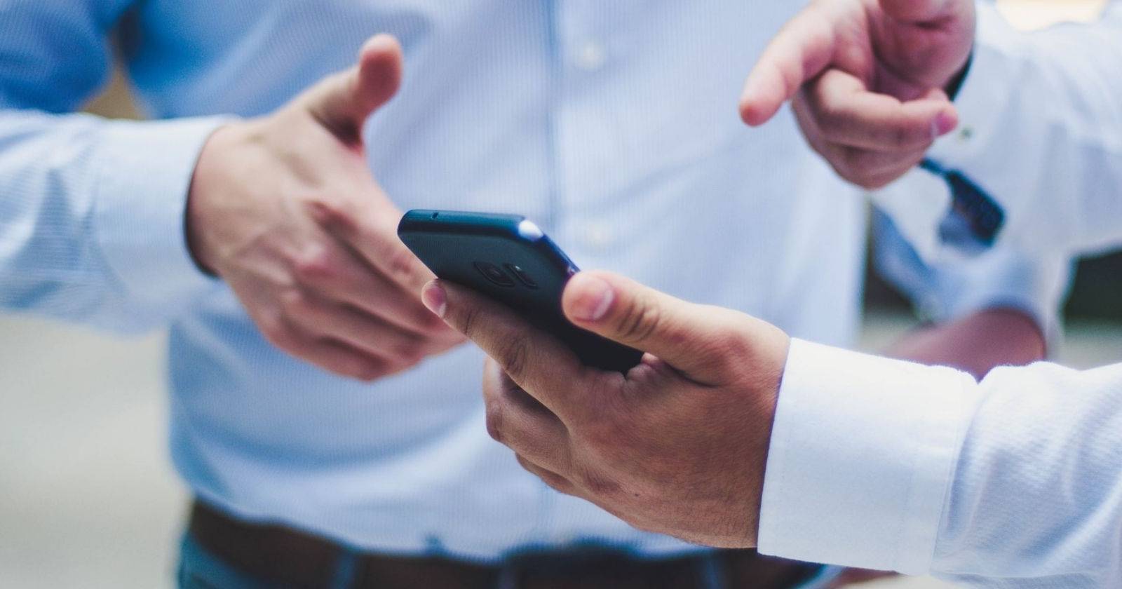 Мужчина показывает другому человеку что-то на смартфоне