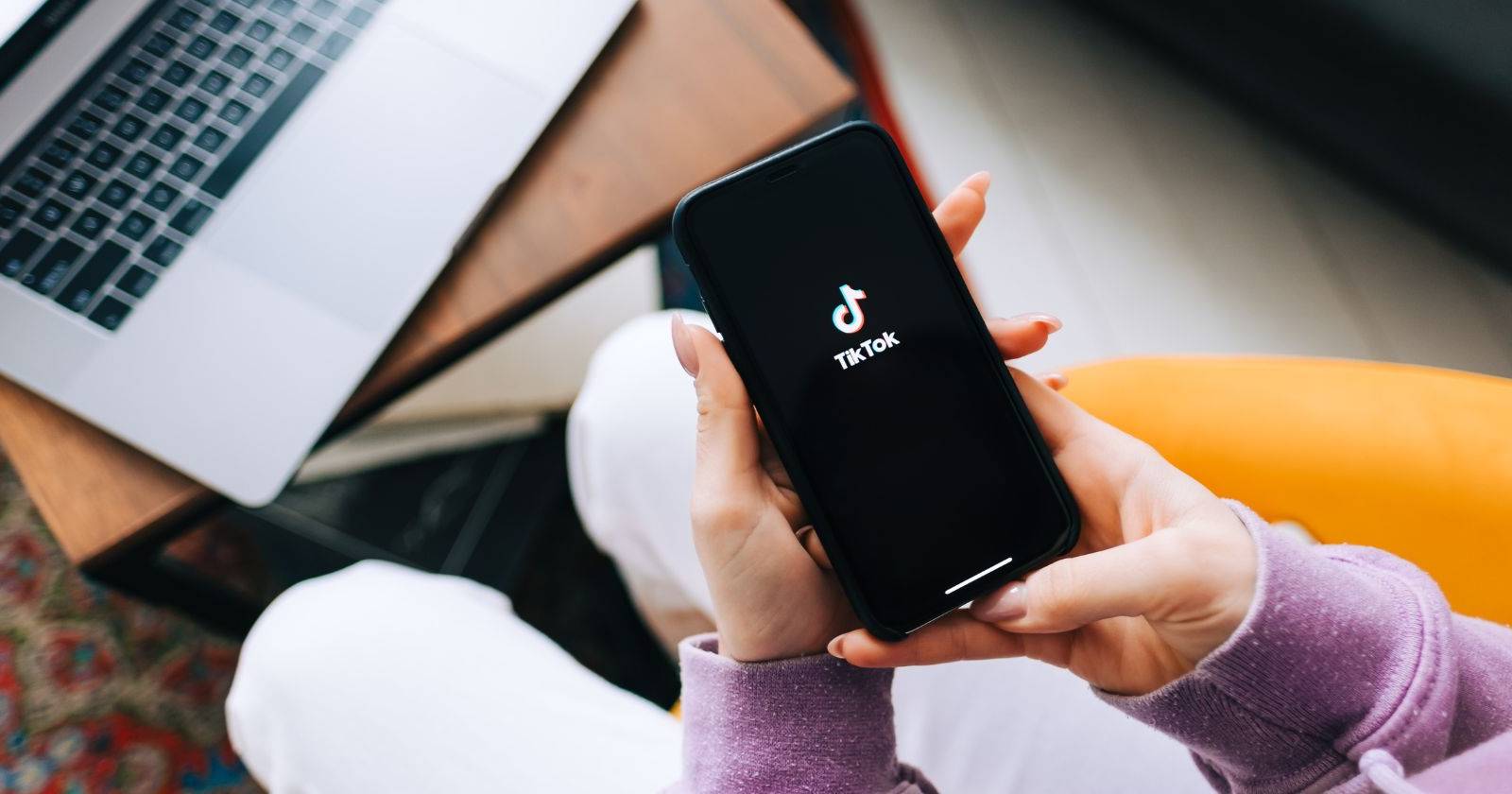 женщина держит телефон с логотипом TikTok на экране