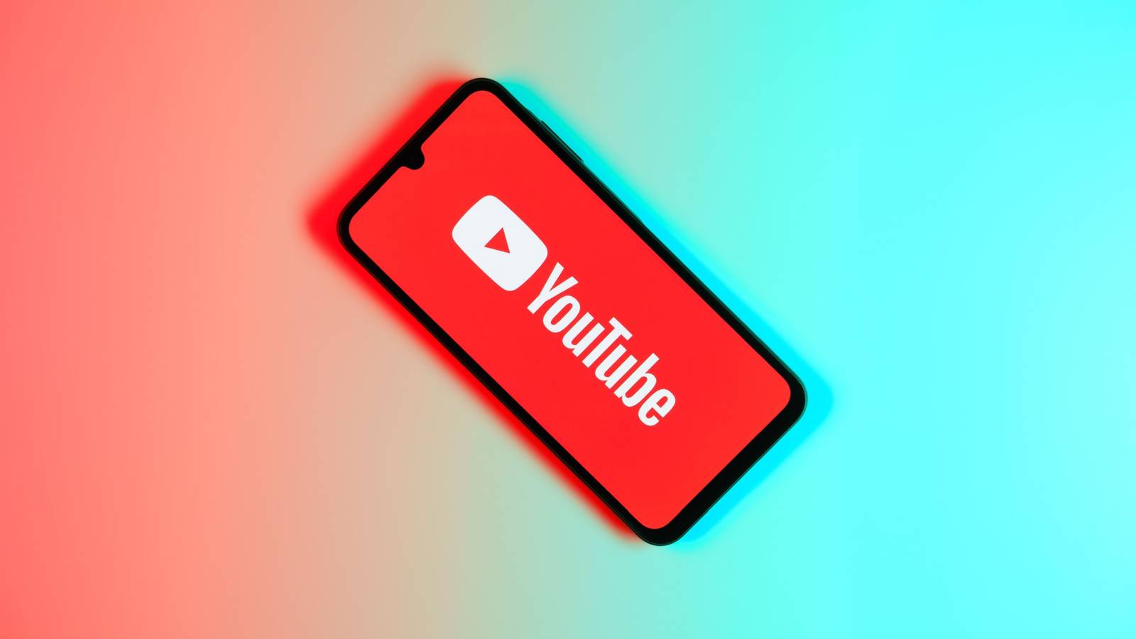 Логотип YouTube на экране телефона на градиентном фоне