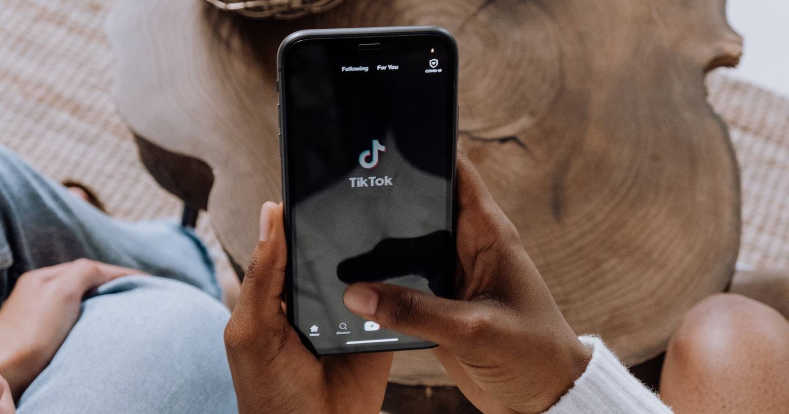 Женщина держит телефон с приложением TikTok на экране