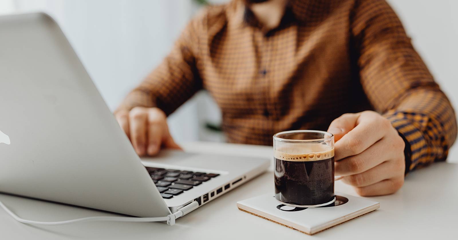 Человек за MacBook с чашкой кофе, рабочая обстановка