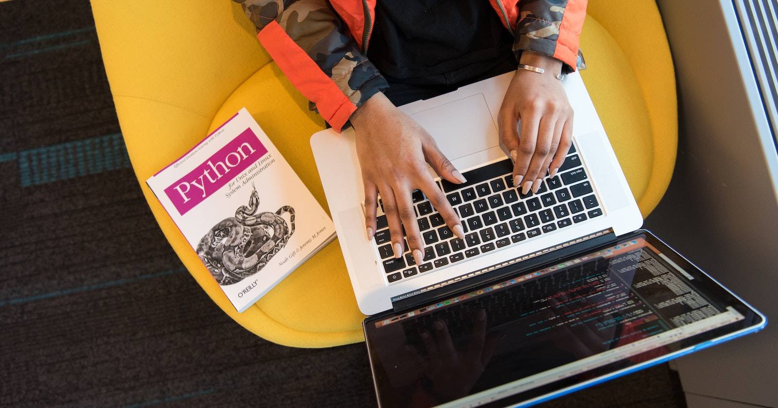 Человек программирует на ноутбуке; на стуле лежит книга по Python