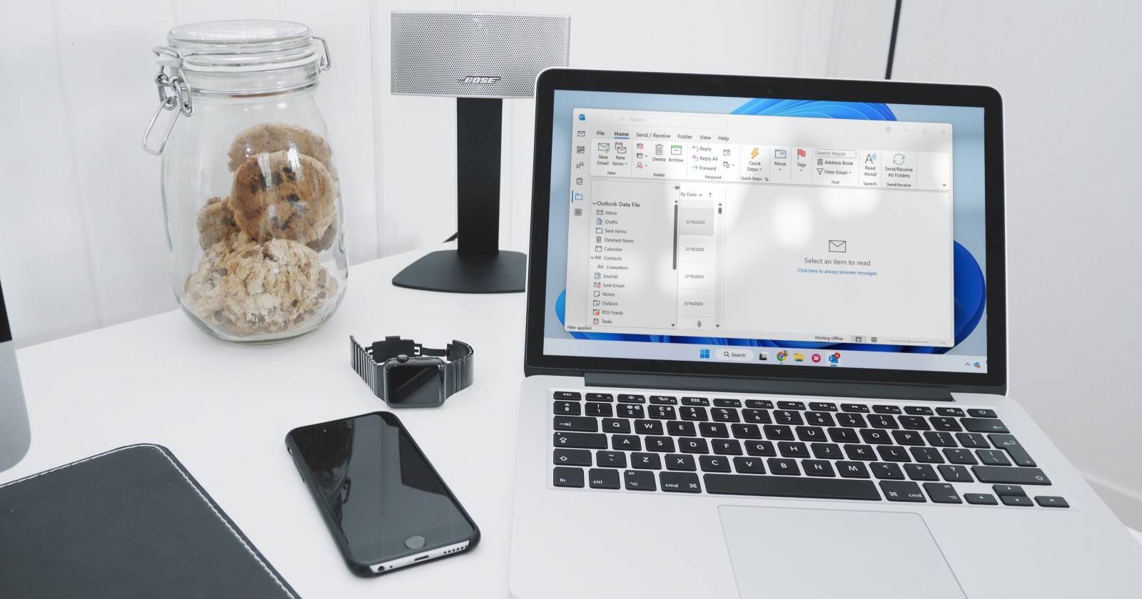 Серебристый ноутбук с запущенным Outlook на белом столе