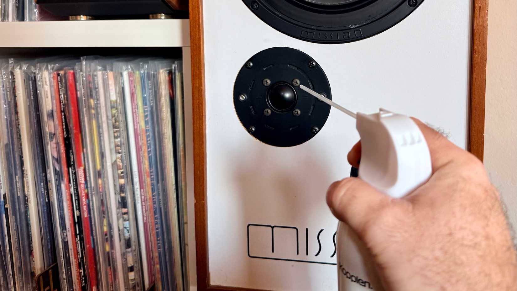 Человек чистит твитер колонок сжатым воздухом, держа баллон на расстоянии.