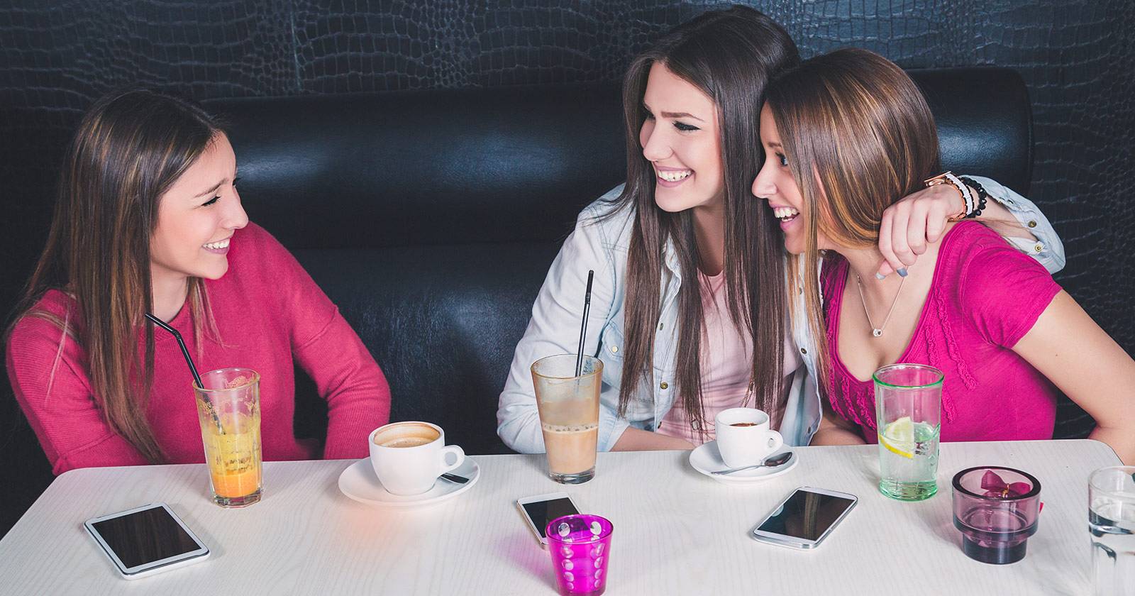 смартфон в руке возле компании друзей в кафе