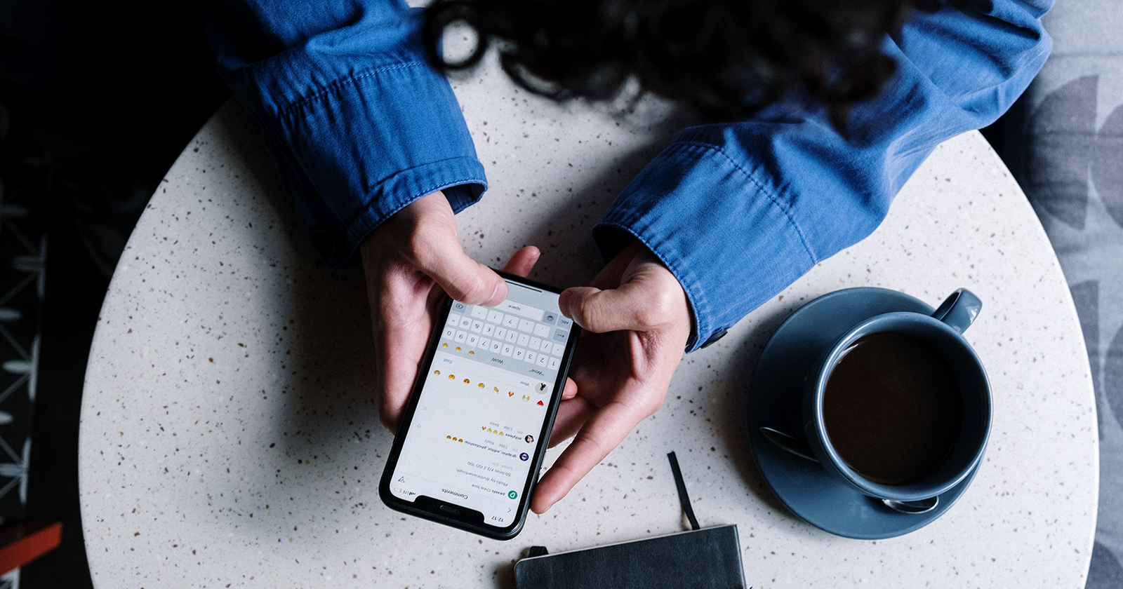 Человек держит iPhone на столе и отправляет сообщение