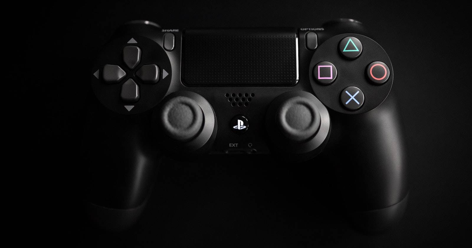 Чёрный контроллер PS4 на тёмном фоне