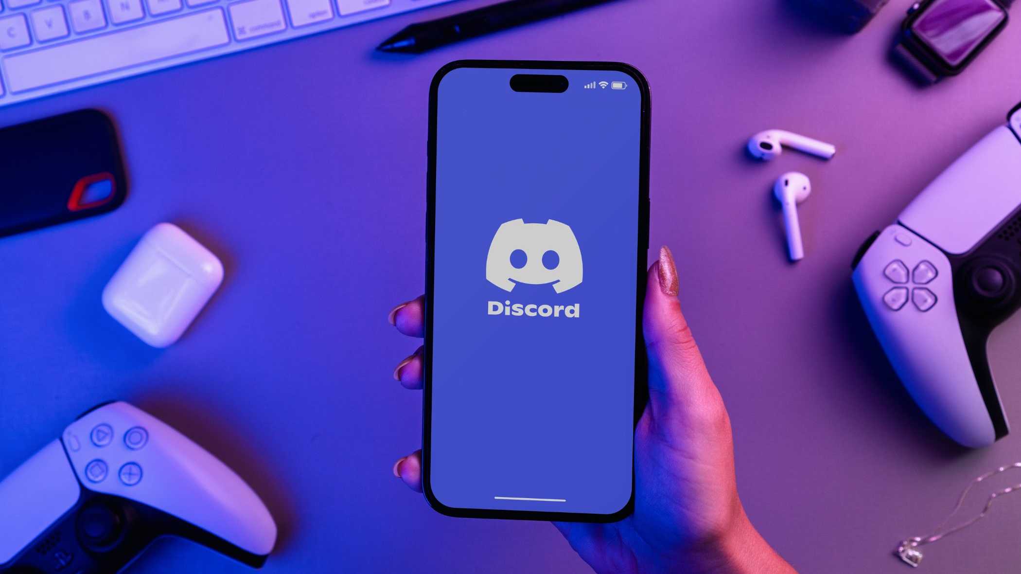 Человек держит смартфон с логотипом Discord