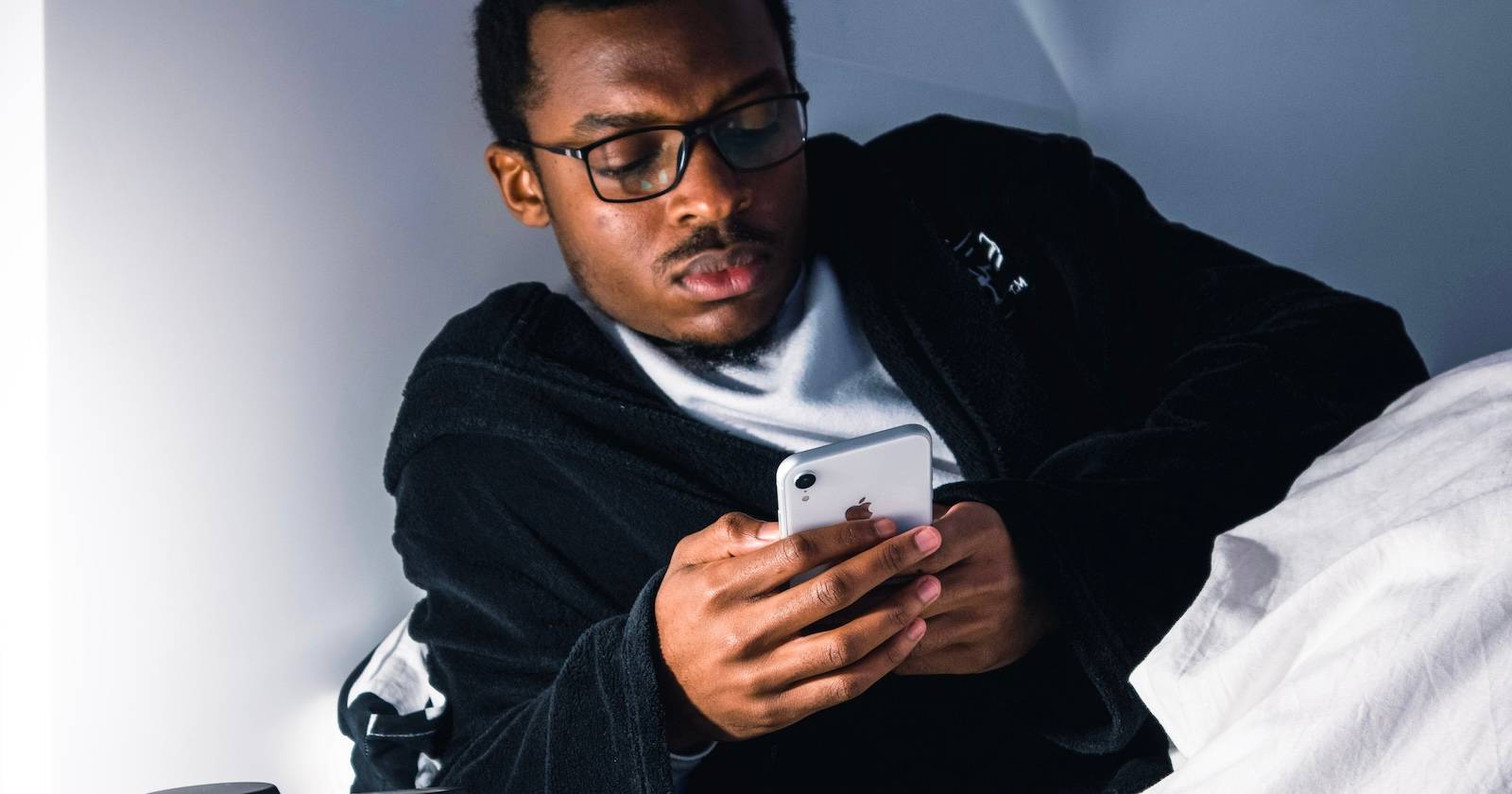 человек держит iPhone в кровати