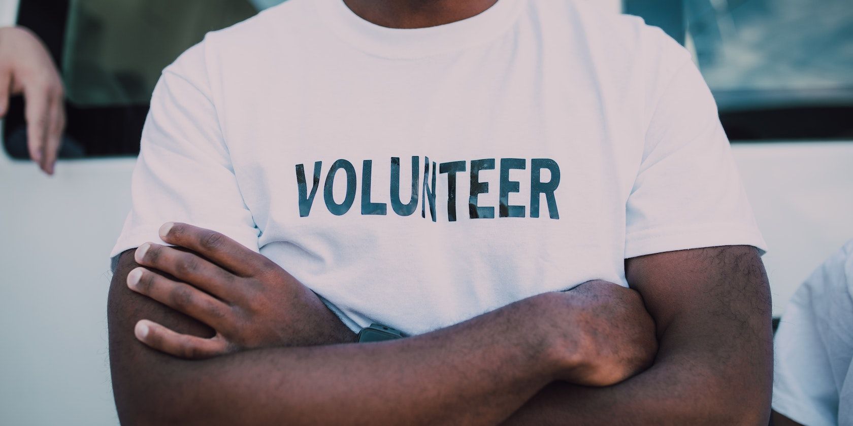 Мужчина в футболке с надписью volunteer