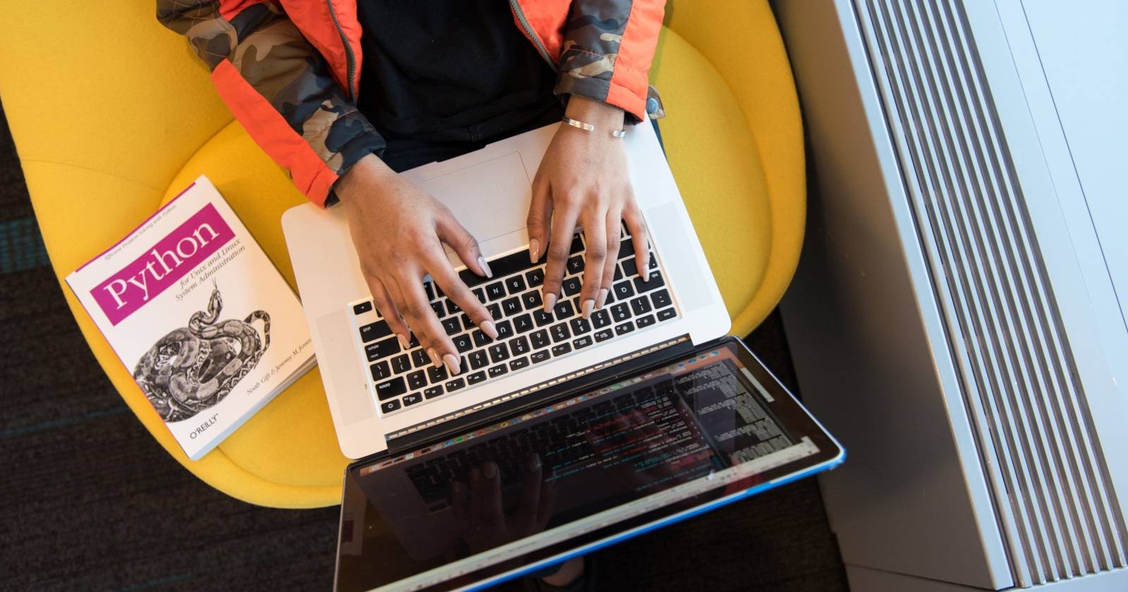 Руки печатают на клавиатуре; на столе блокнот с надписью Python