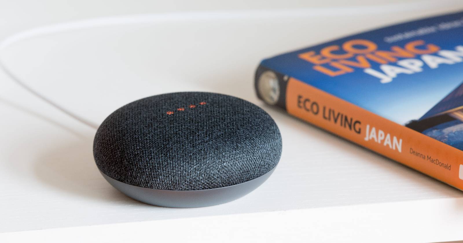 угольный Google Home Mini рядом с книгой
