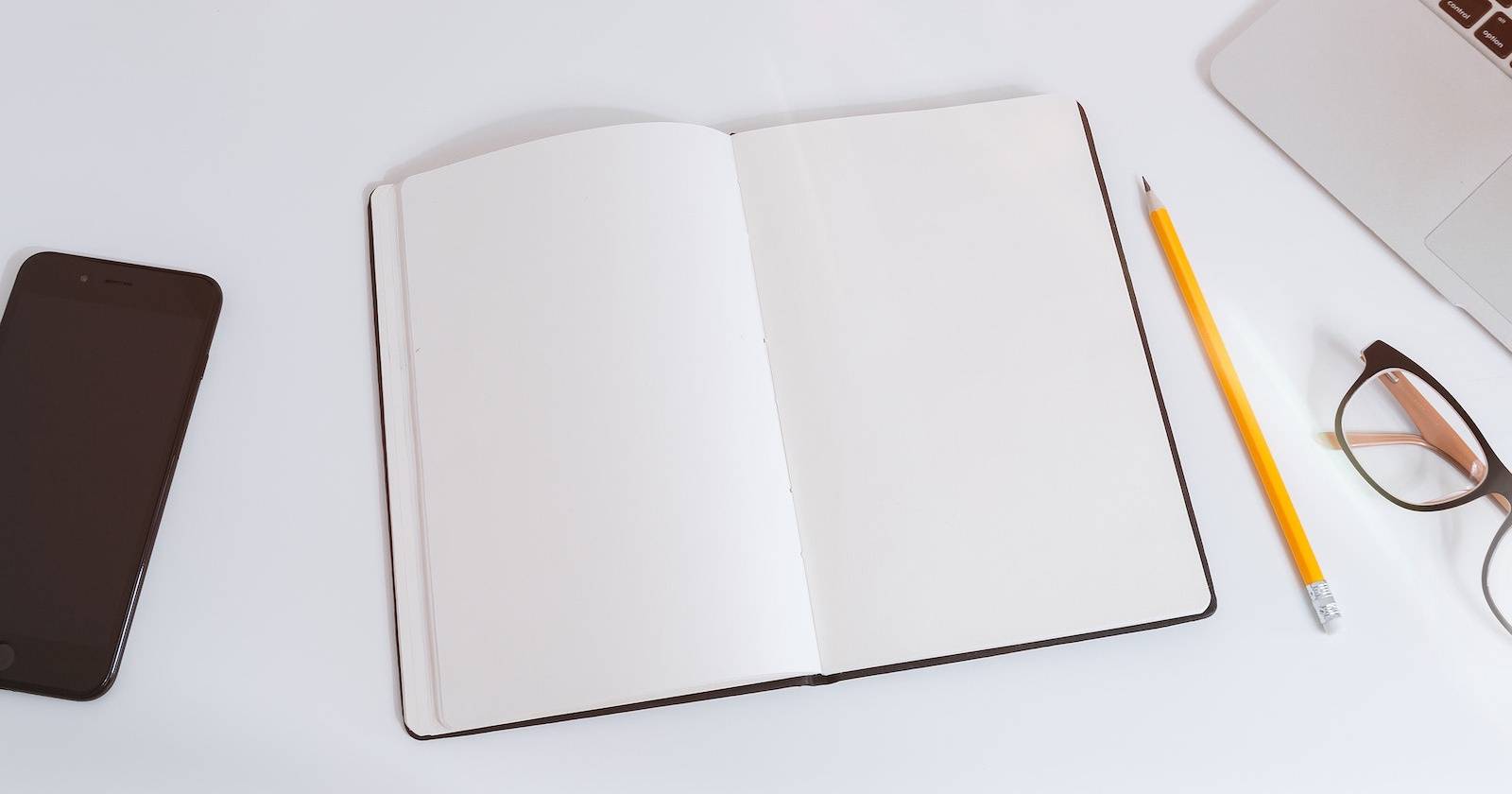 Пустой блокнот, очки и карандаш на столе