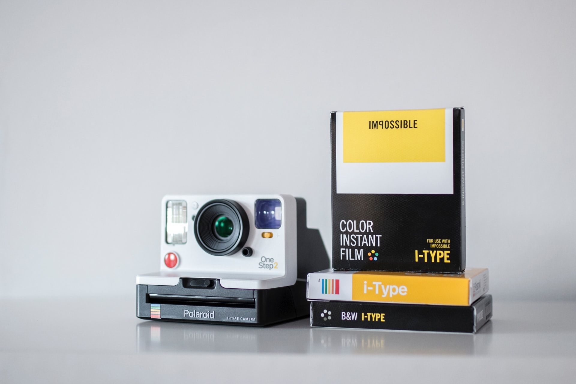 белый Polaroid OneStep 2 рядом с цветной i-type плёнкой и черно-белой