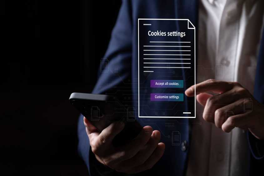 Человек держит телефон; над экраном плавают элементы с опциями согласия на cookies
