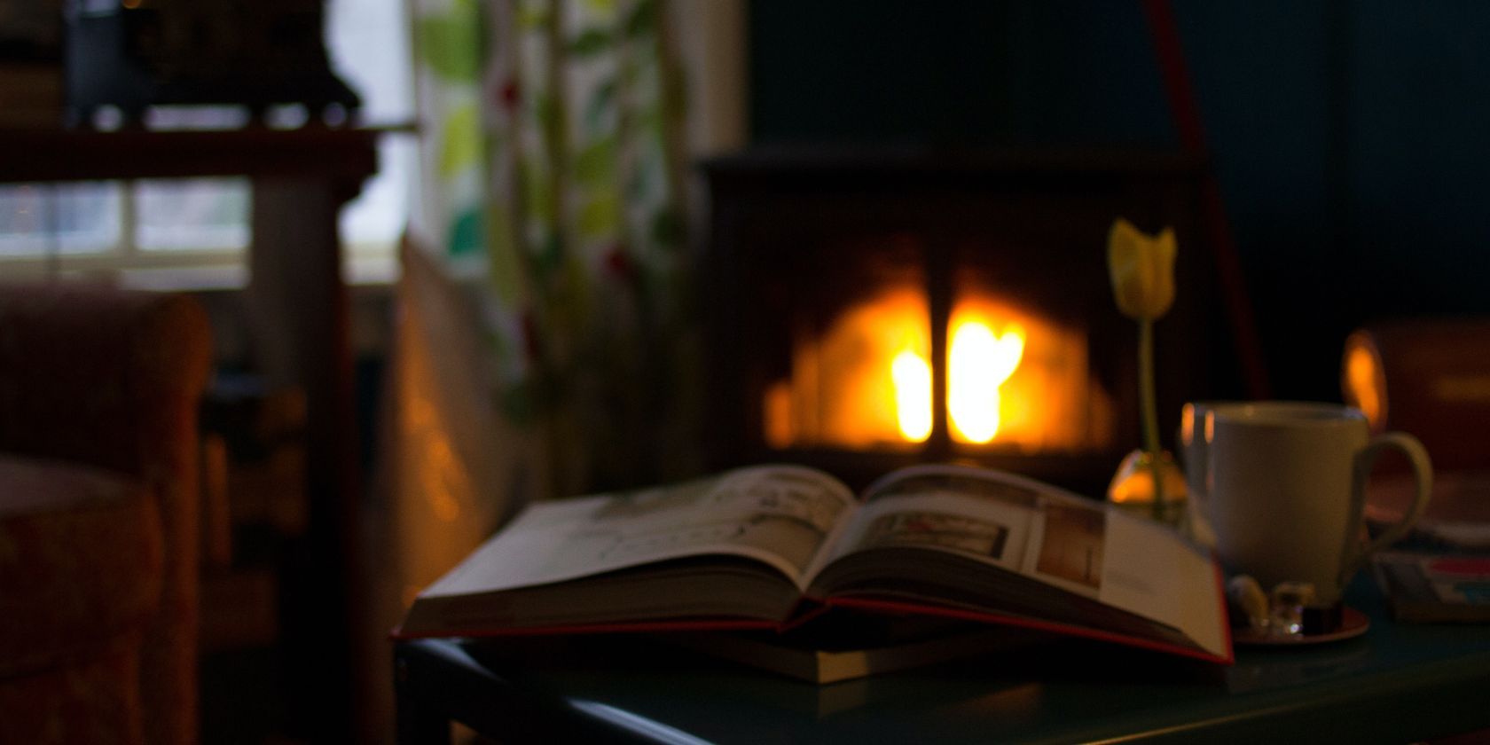 Открытая книга на столе в слабо освещённой комнате