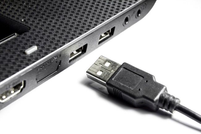 Ноутбук с USB‑разъёмами и кабелем на белом фоне