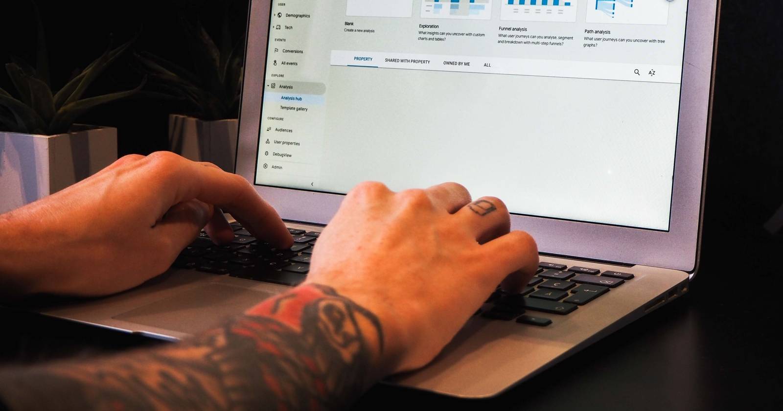 Um homem digitando no teclado de um laptop, manipulando dados em um painel.