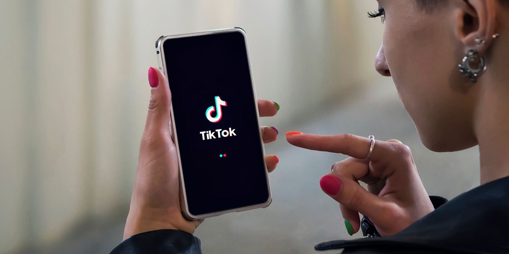 Женщина с телефоном, на экране логотип TikTok