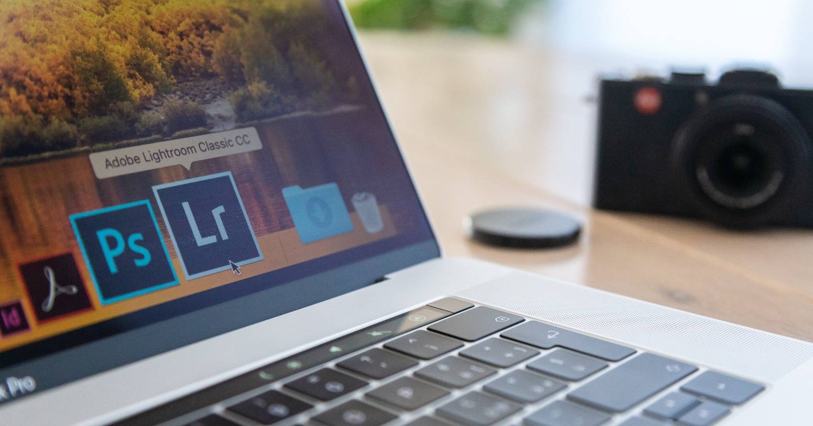 Ноутбук MacBook с открытым Adobe Lightroom на фоне плёночной камеры