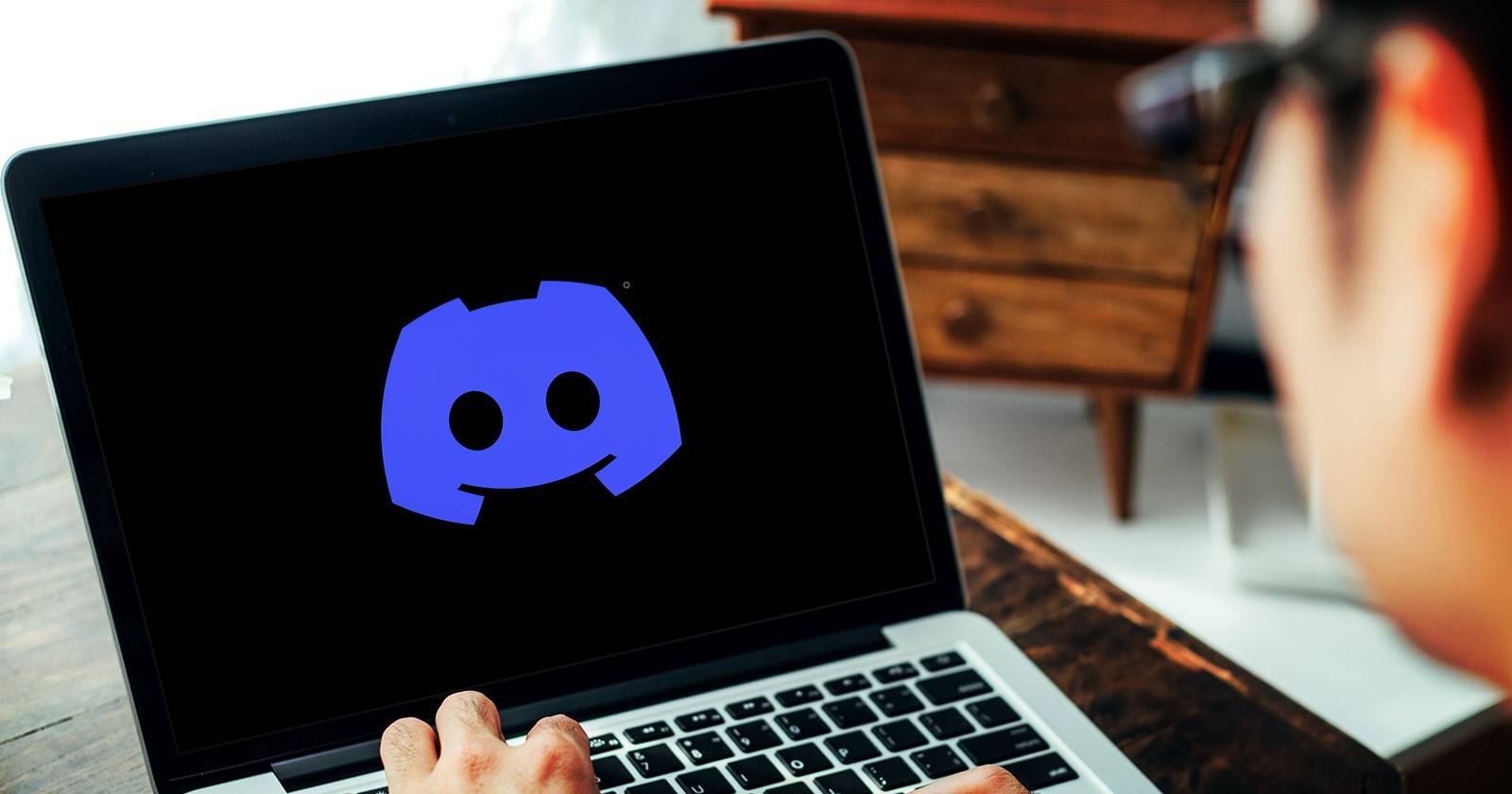 человек пользуется ноутбуком с логотипом Discord на экране