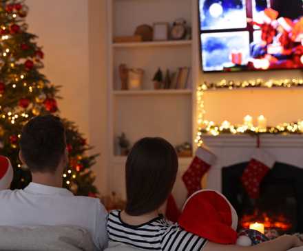 Семья смотрит рождественский контент на телевизоре