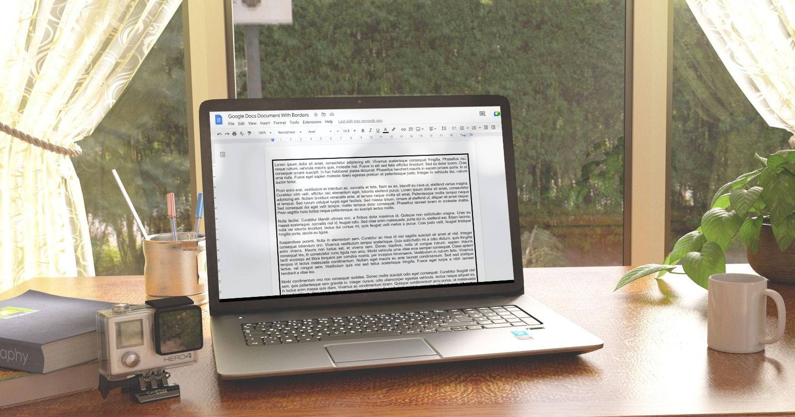 Документ Google Docs с рамкой на экране ноутбука, размещенного на рабочем столе у окна