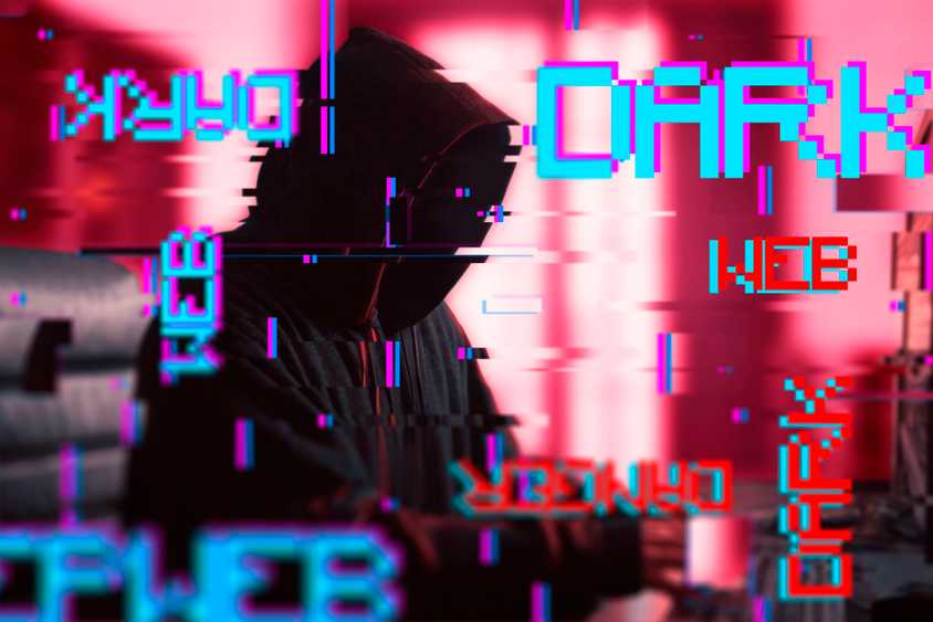 тёмный хакер в плаще перед компьютером с графическим помехами