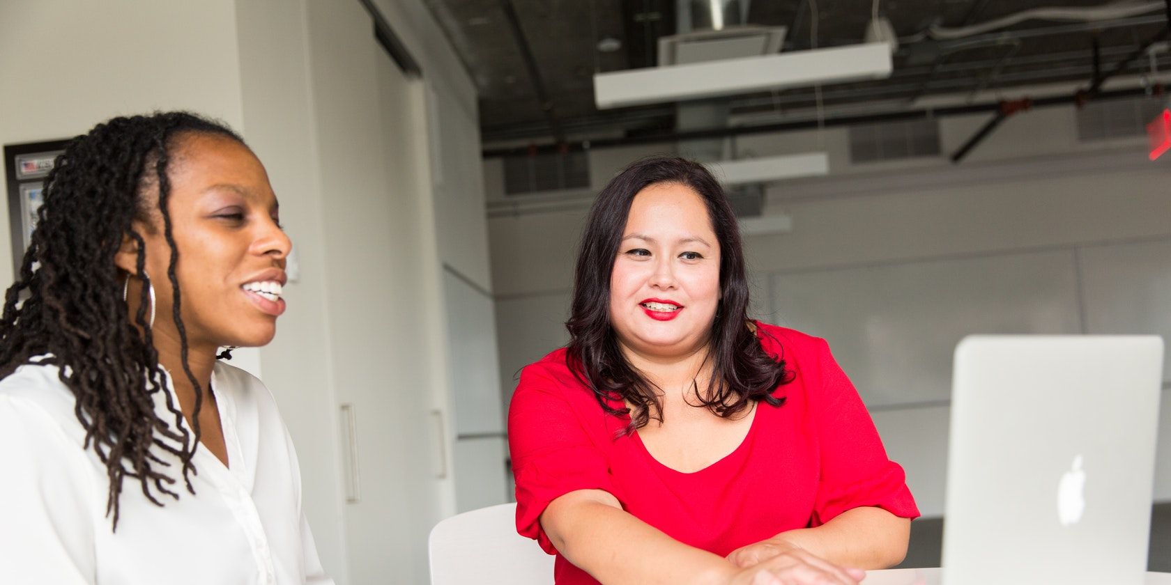 Женщина беседует с другой женщиной, перед ними ноутбук