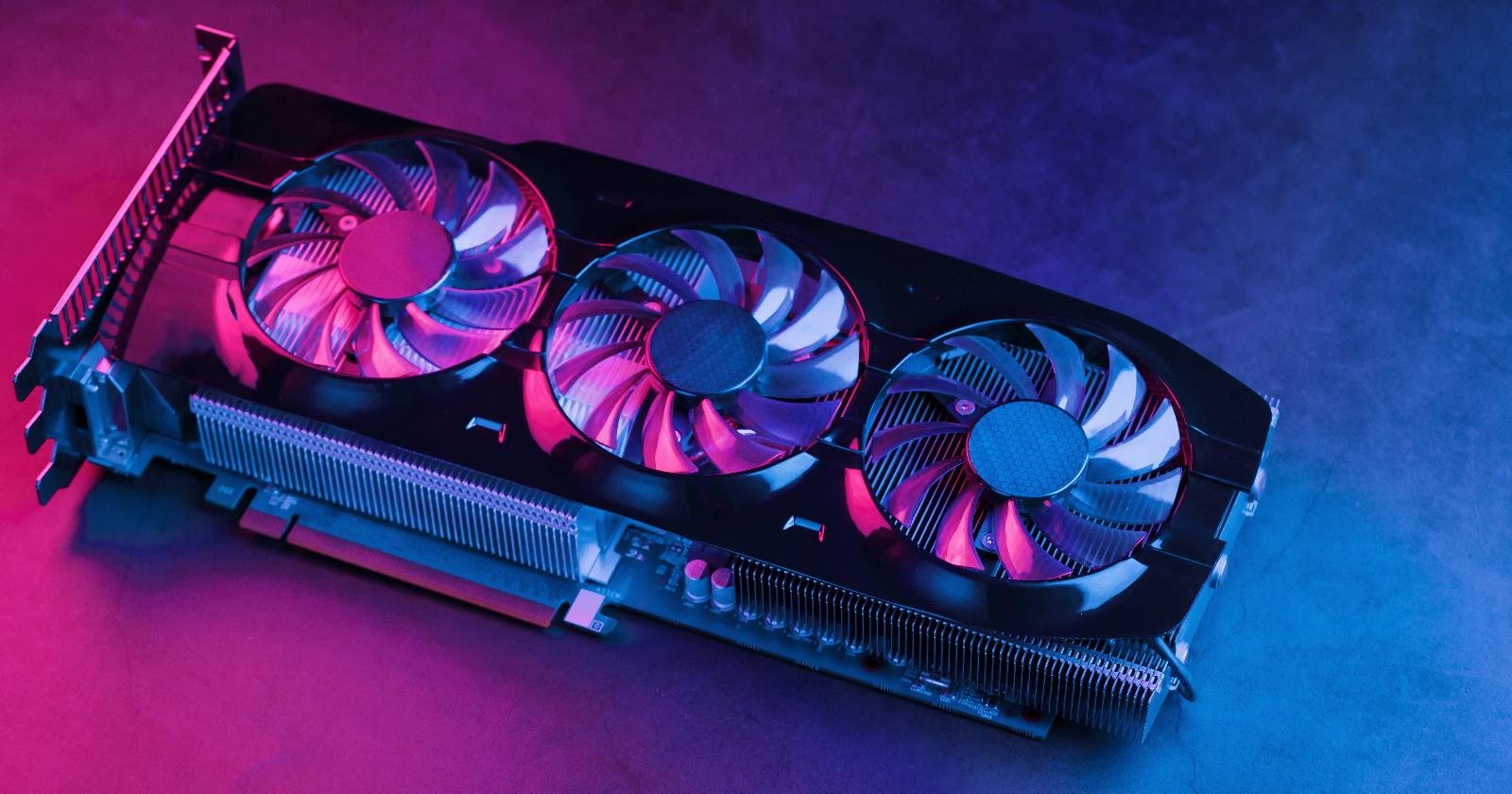 Большая мощная видеокарта с тремя вентиляторами и неоновым сине-розовым освещением, вид сверху