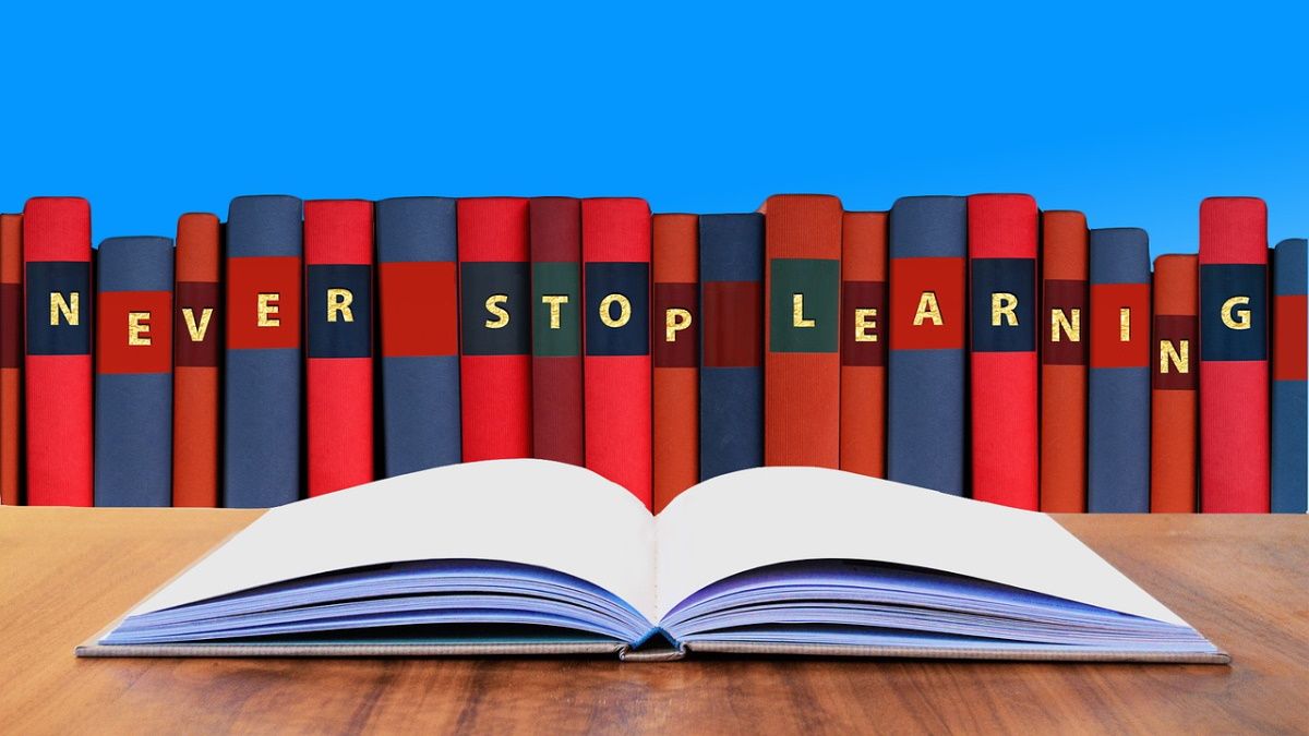 Открытая книга на столе, на заднем плане другие книги.