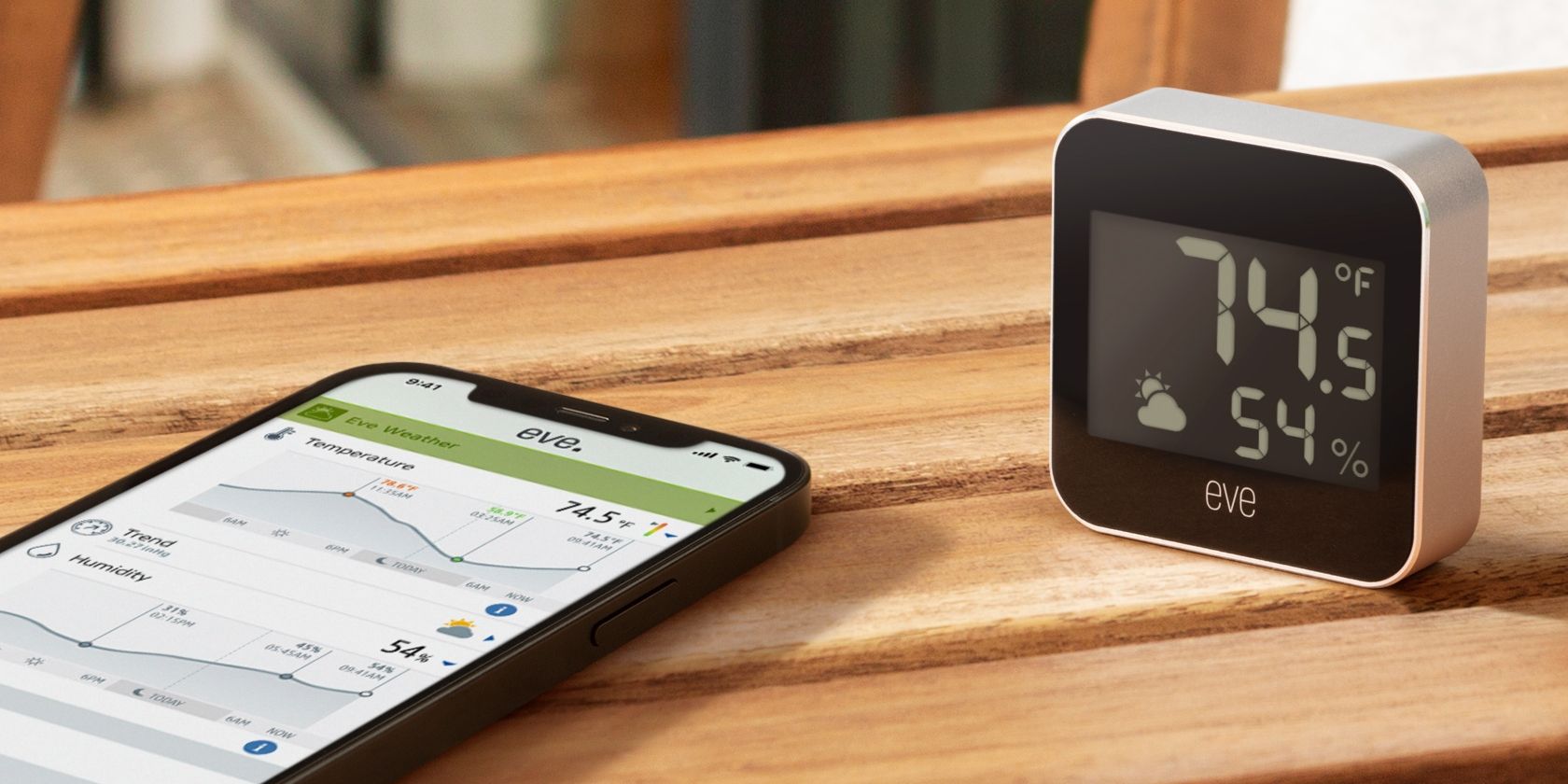 Eve Weather Sensor on a table outdoors next to an iPhone