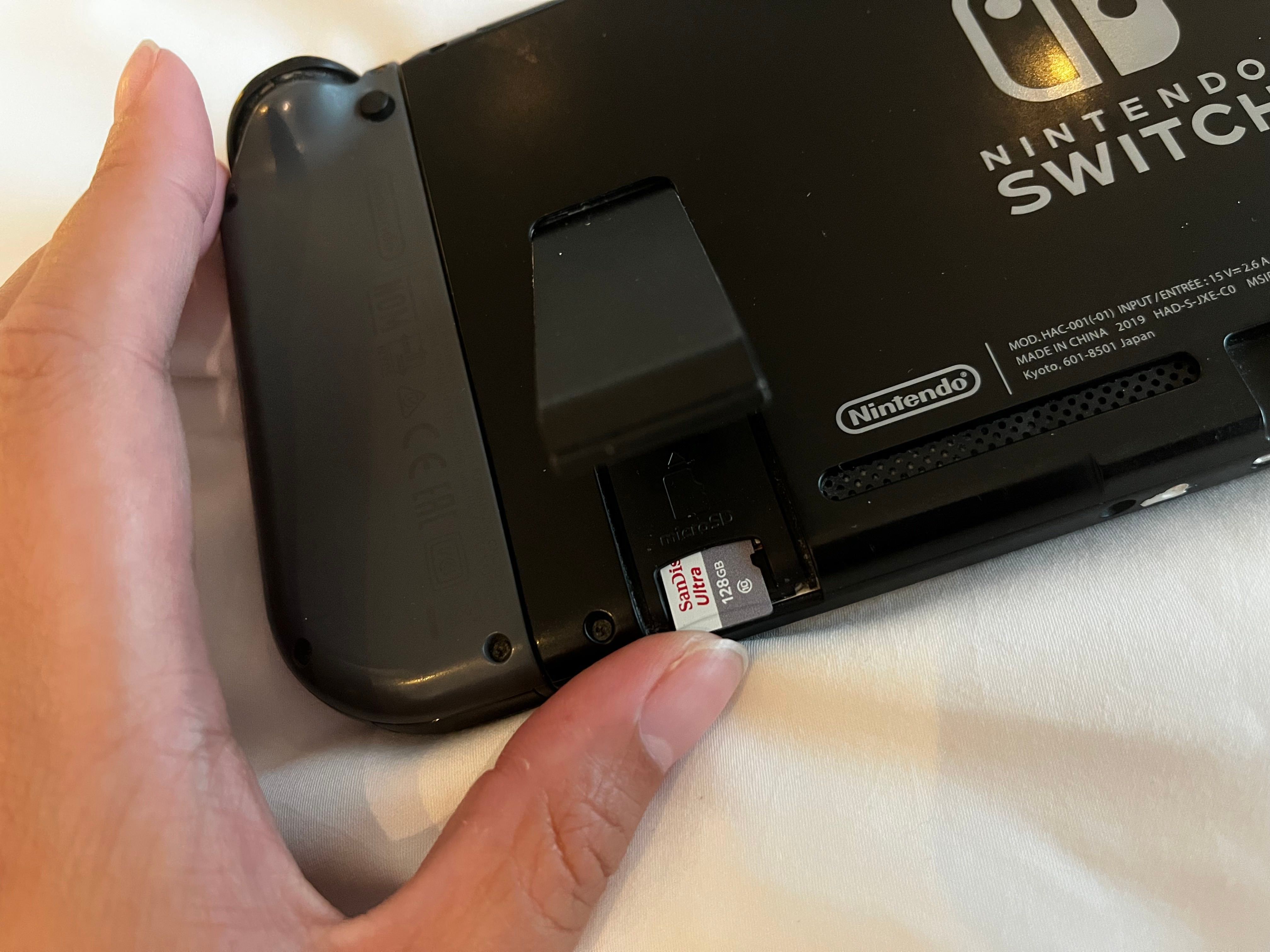 Вставка microSD-карты в слот Nintendo Switch, этикетка от консоли