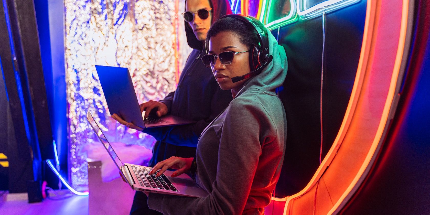 Мужчина в зелёном худи и чёрных солнцезащитных очках, сидящий на оранжевом кресле