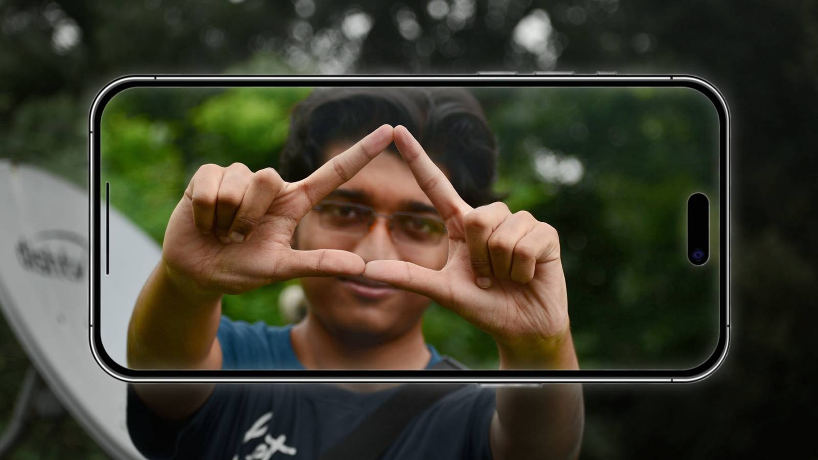 Smartphone capturing photo of guy forming triangle with hands
