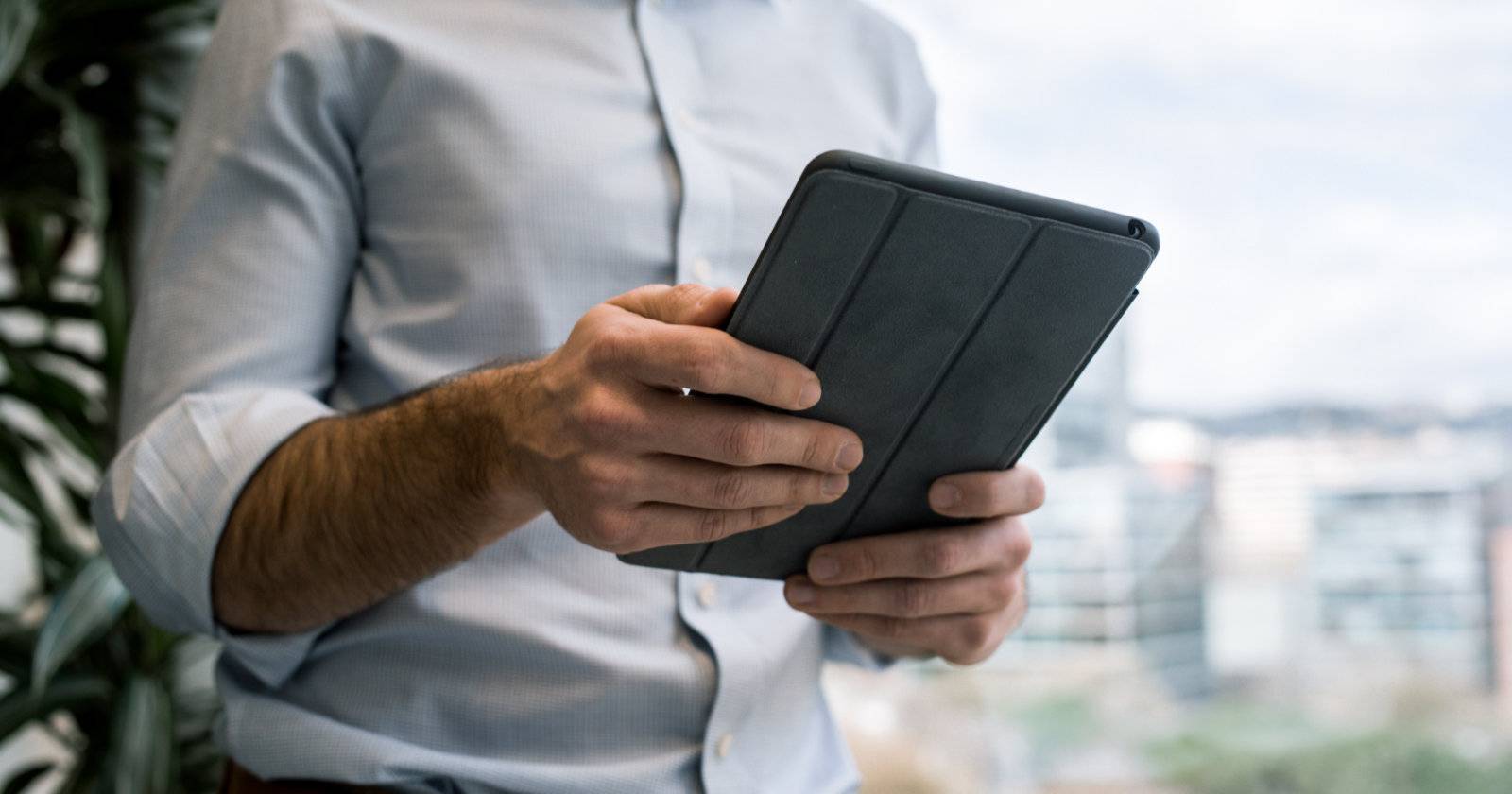 Человек держит iPad в руках, экран устройства виден крупным планом