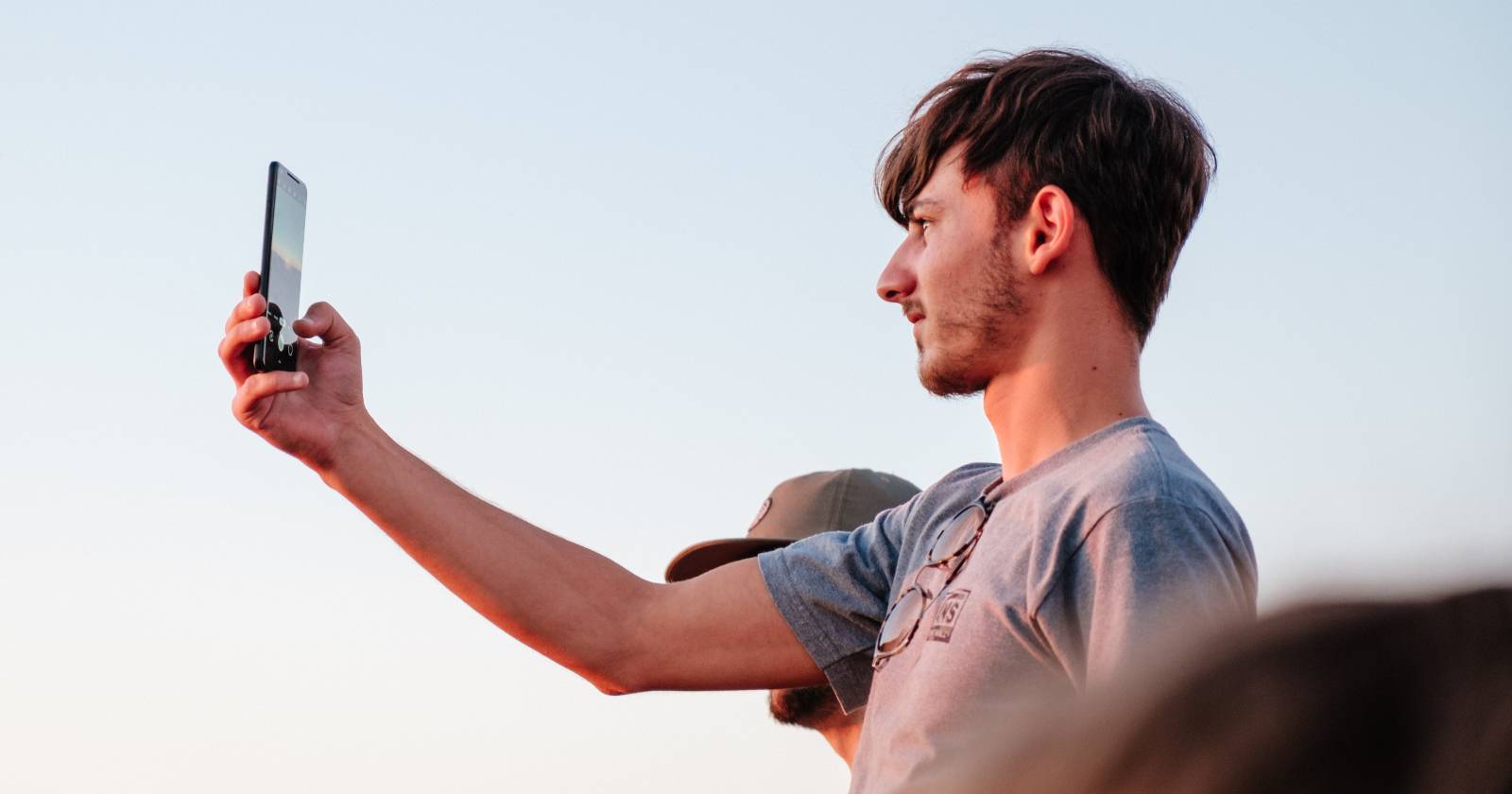 Фото человека, делающего снимок на фоне заката