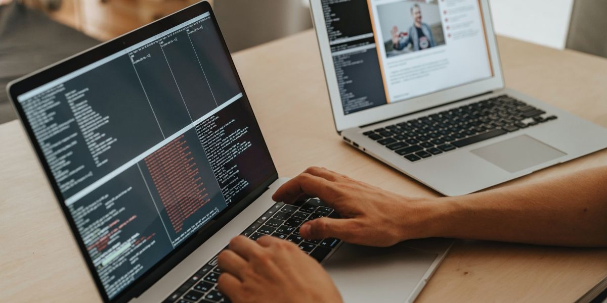 крупный план рук, печатающих на ноутбуке; рядом открыт второй ноутбук