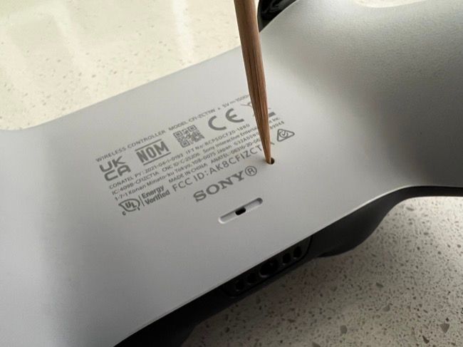 Сброс DualSense с помощью тонкого предмета.