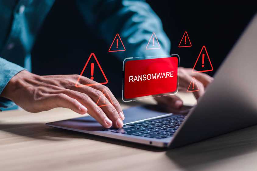 Person on laptop with Ransomware icon hovering above it