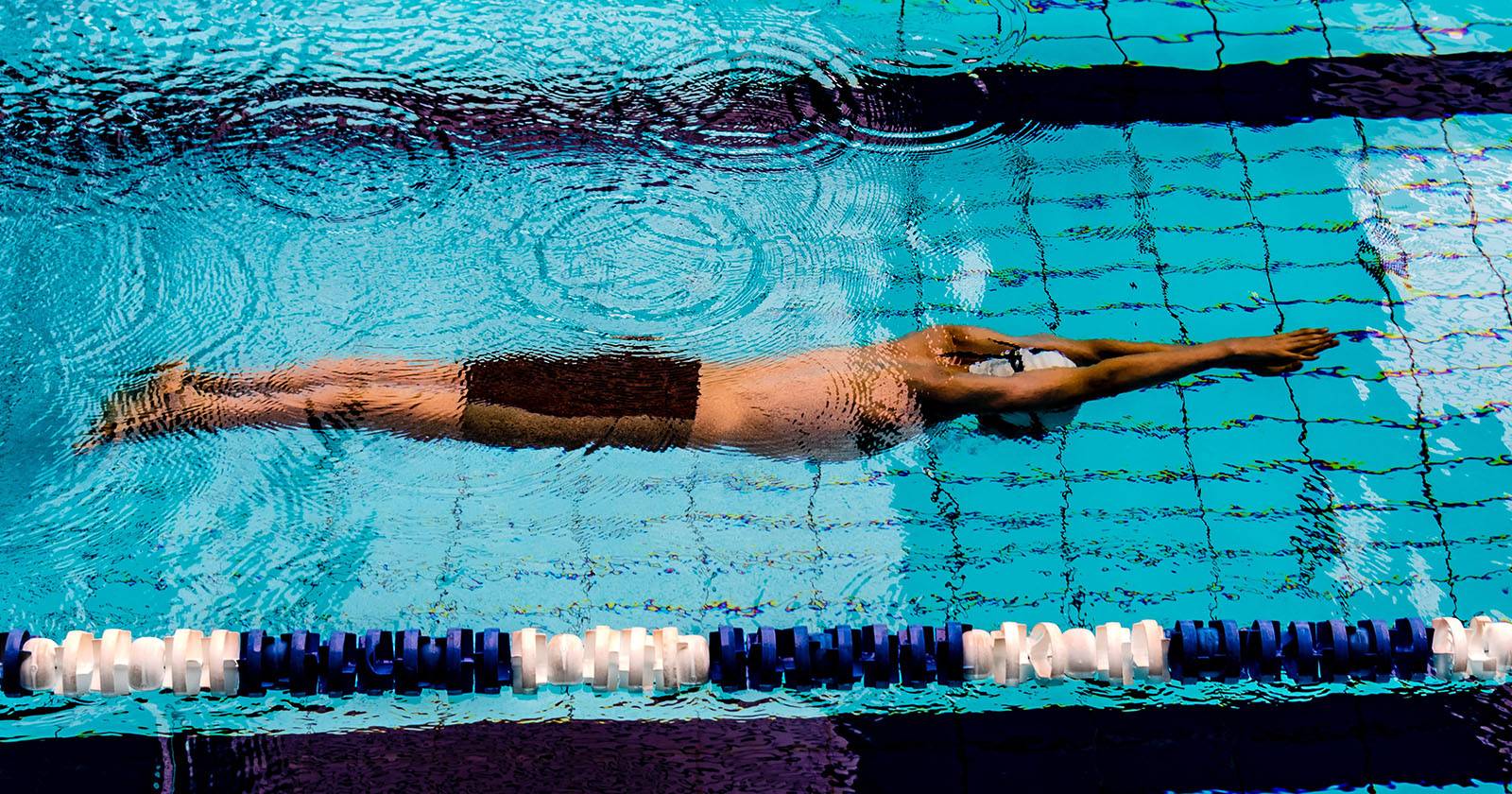 Человек плавает в бассейне, запечатлён сверху