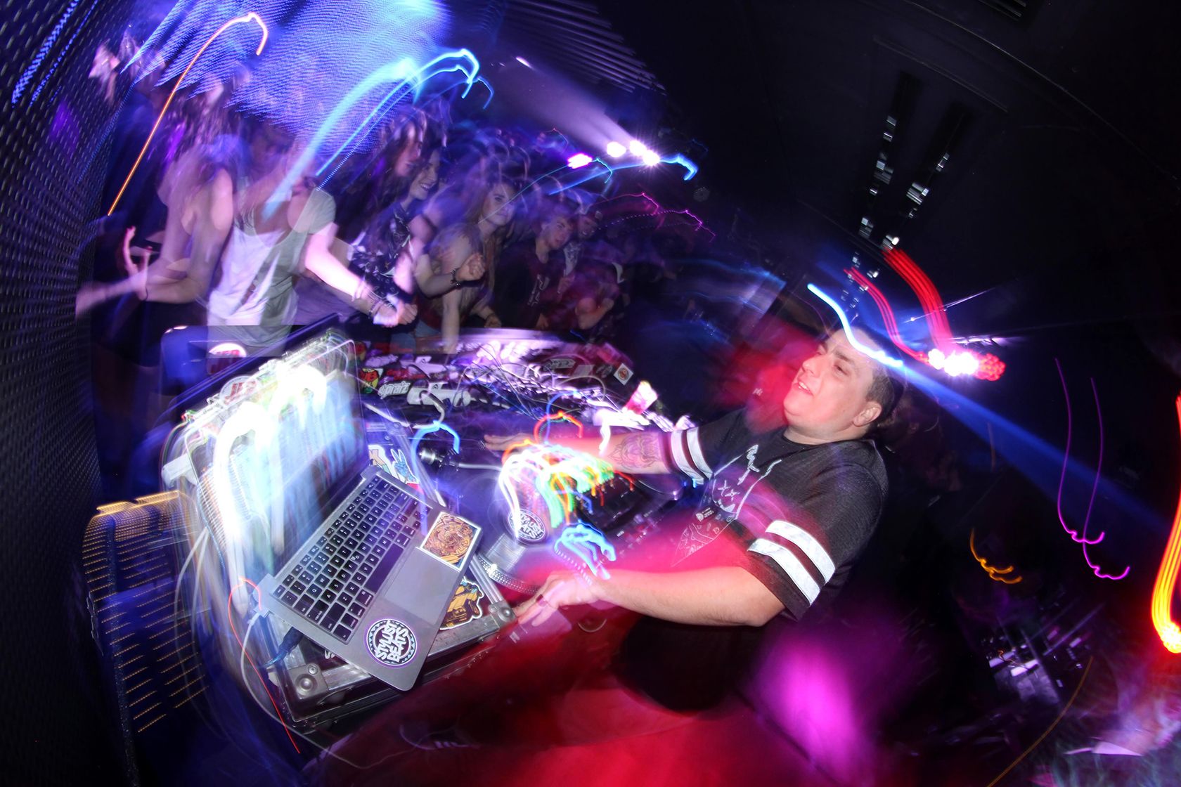DJ работает в клубе, лучи света расходятся во все стороны.