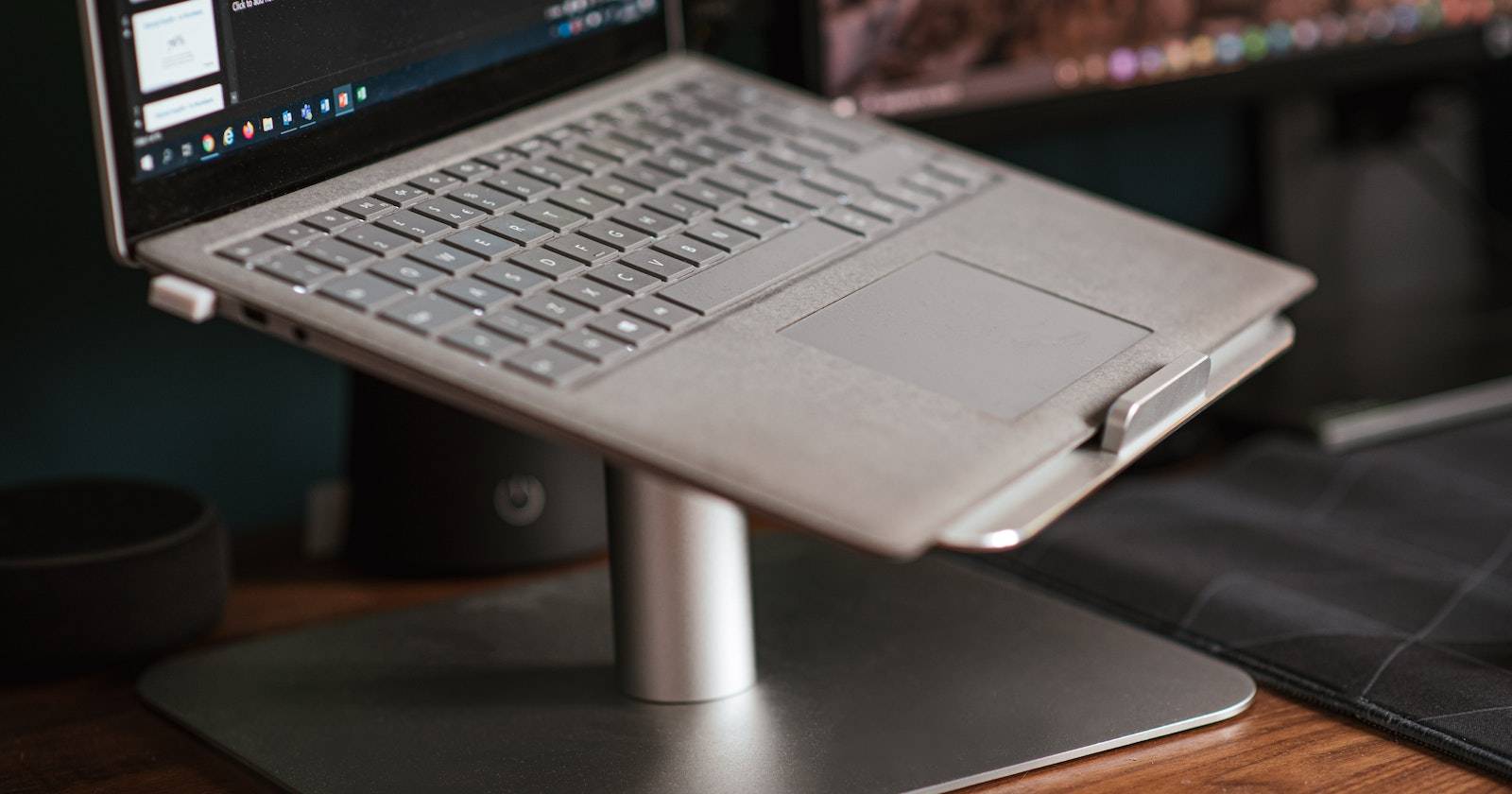 A laptop placed on a stand, on a table.