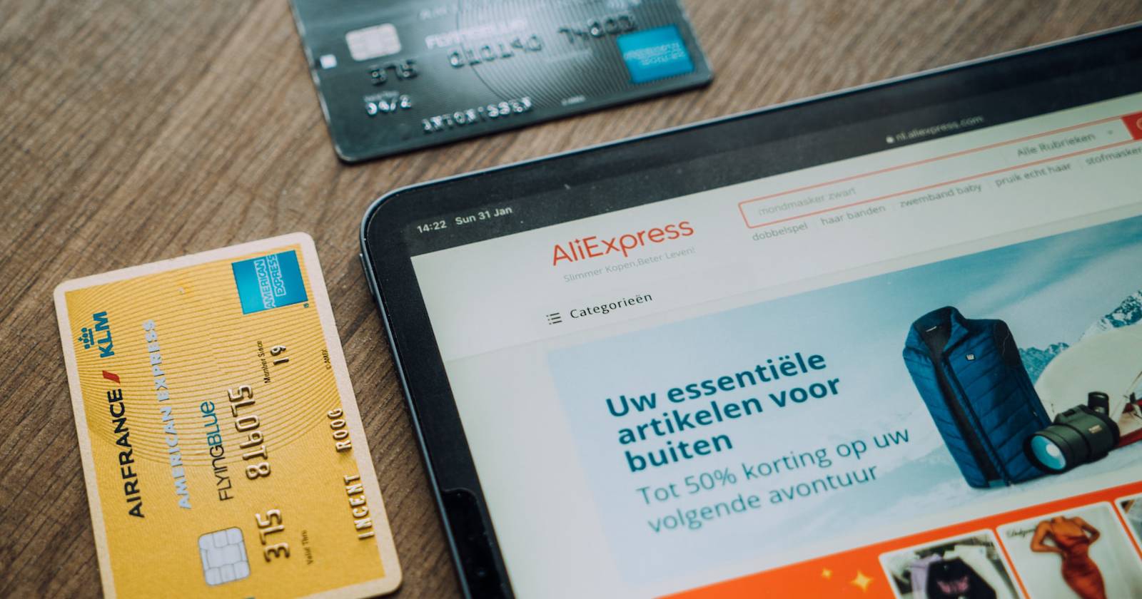 Веб-сайт AliExpress на планшете и банковские карты на столе
