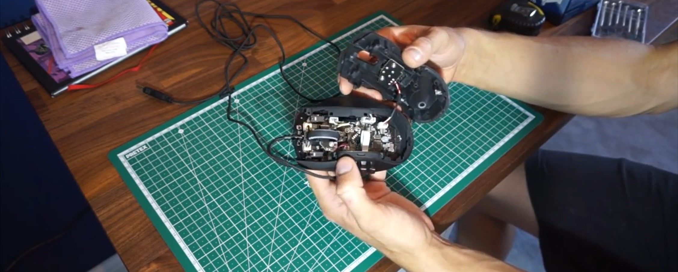 Человек отсоединяет кабель подсветки от верхней панели мыши