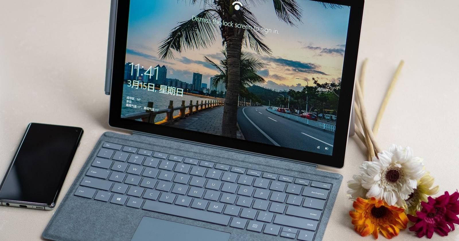 Устройство Surface на столе рядом с цветами и телефоном