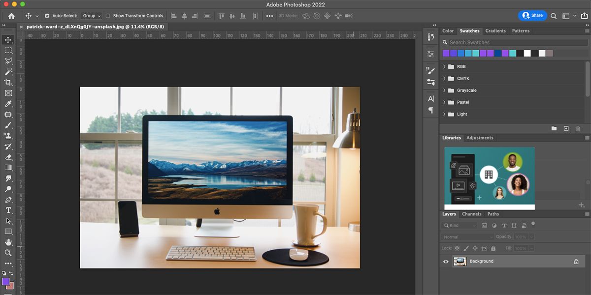 Фотография рабочего стола Mac с iPhone рядом и кружкой кофе.
